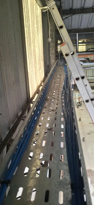 Bandeja portacables larga con cables azules y negros en el techo de la nave