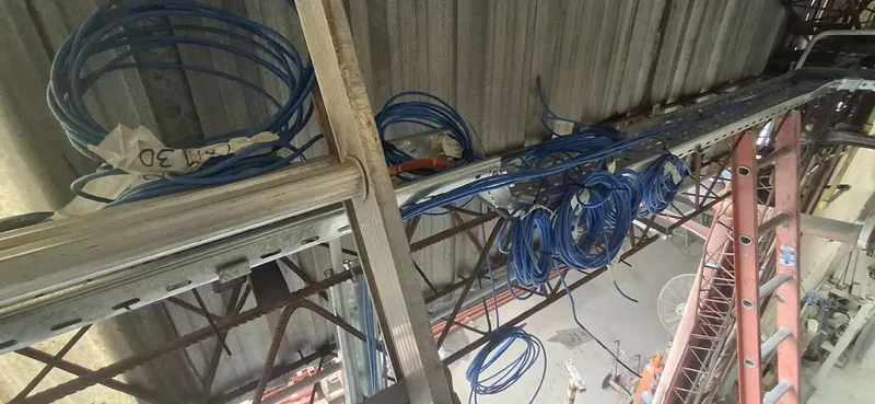 Cables azules en bandeja y rollos de cable con rótulos, en altura
